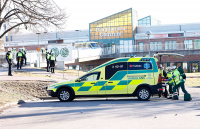 En mann som er skutt i beinet, tas hånd om av politi og ambulansepersonell.